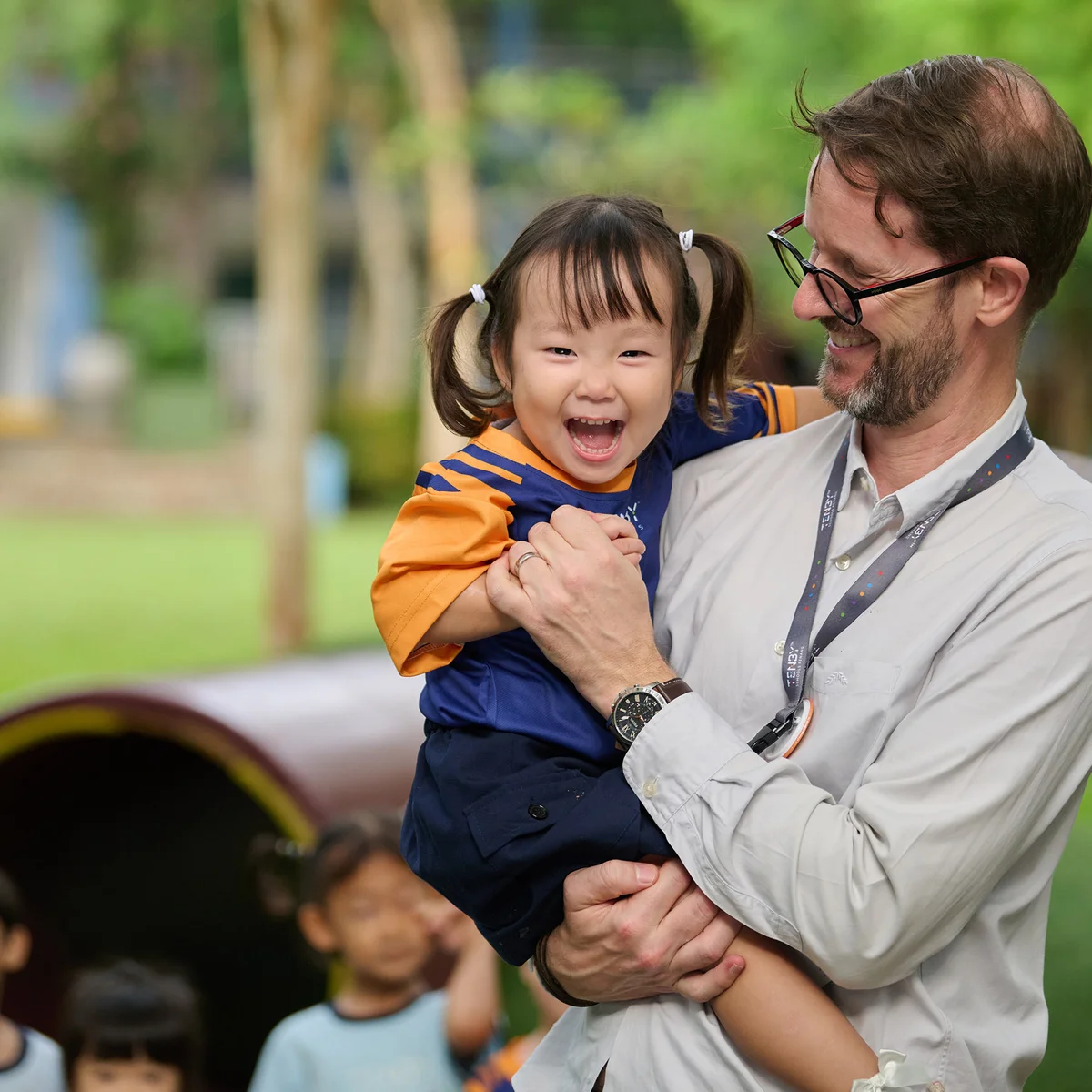 Teacher holding a kindergarten student in his hands