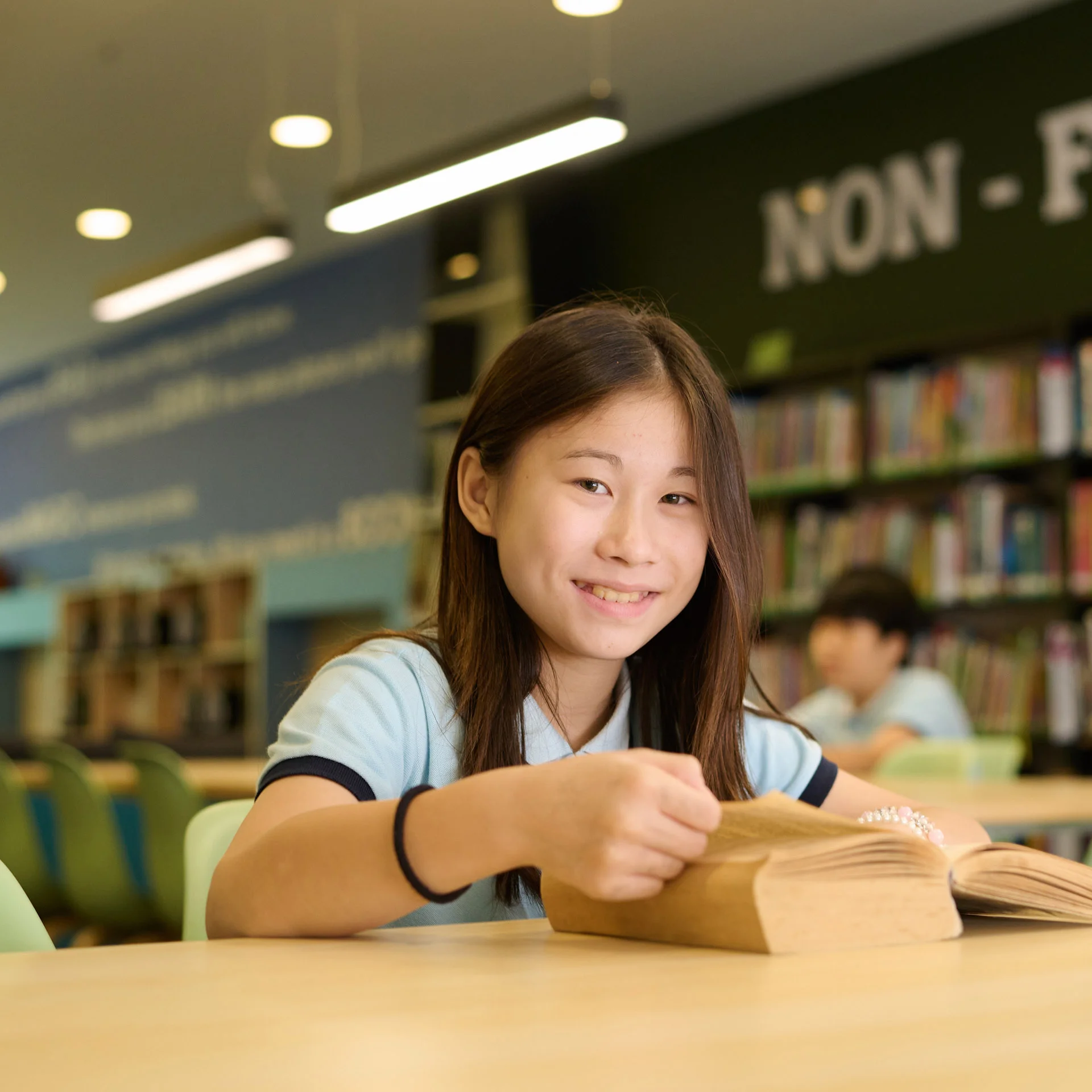 Girl smiling while holding a page from a book