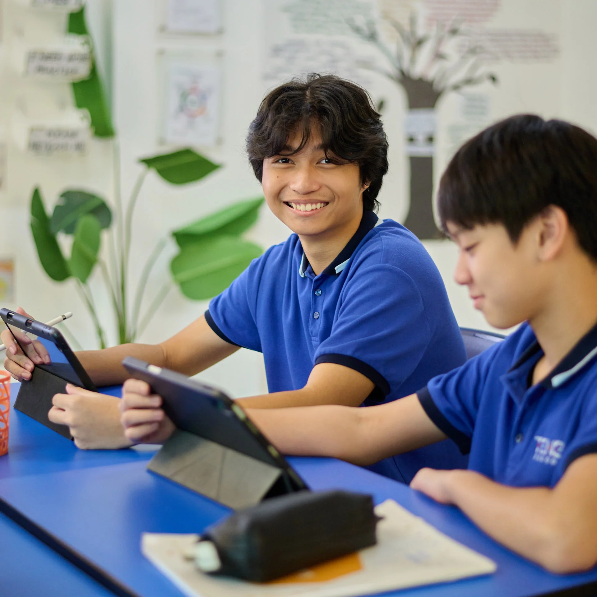 Teenagers smiling while holding their tablets
