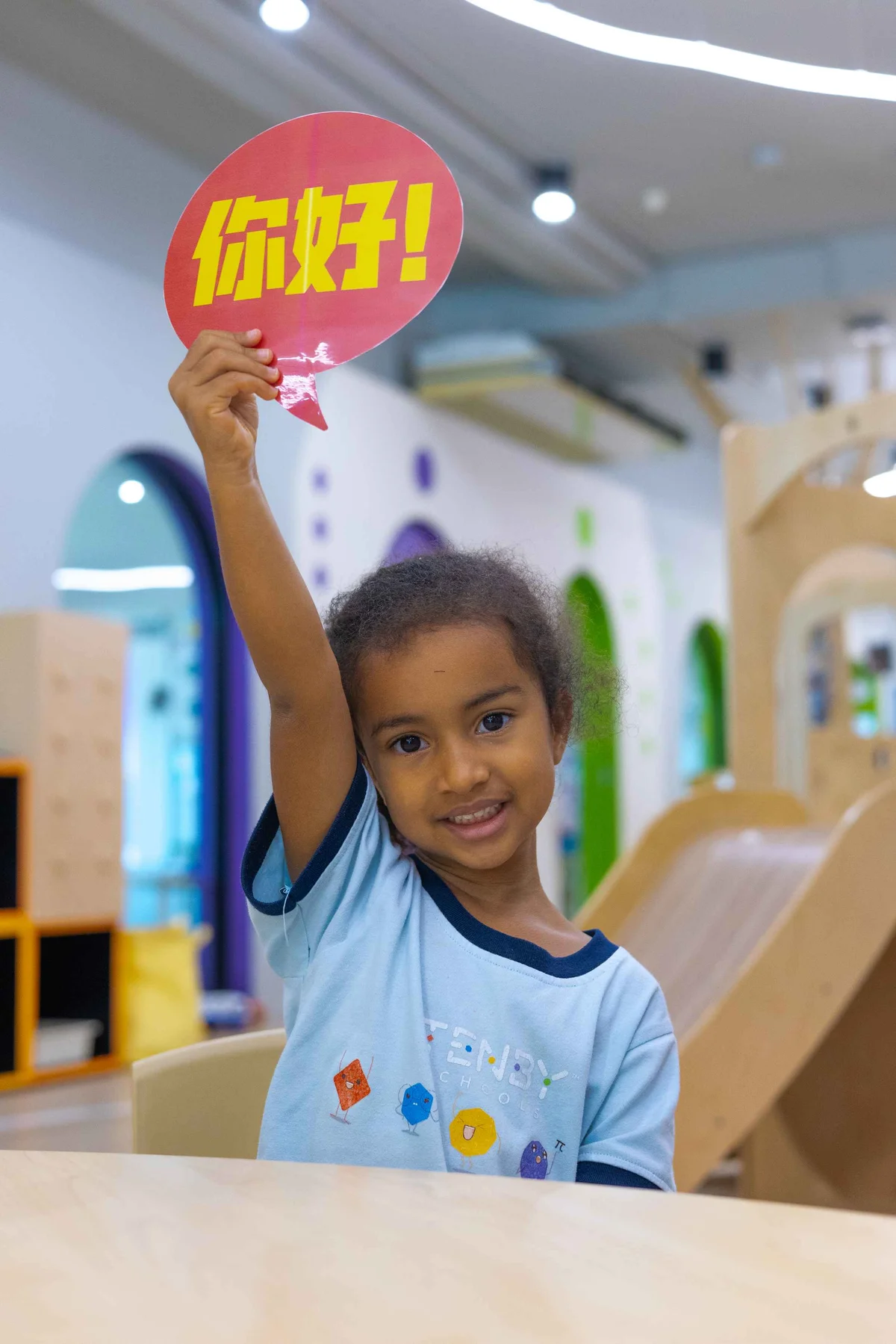 Young girl smiling and holding a greeting sign 
