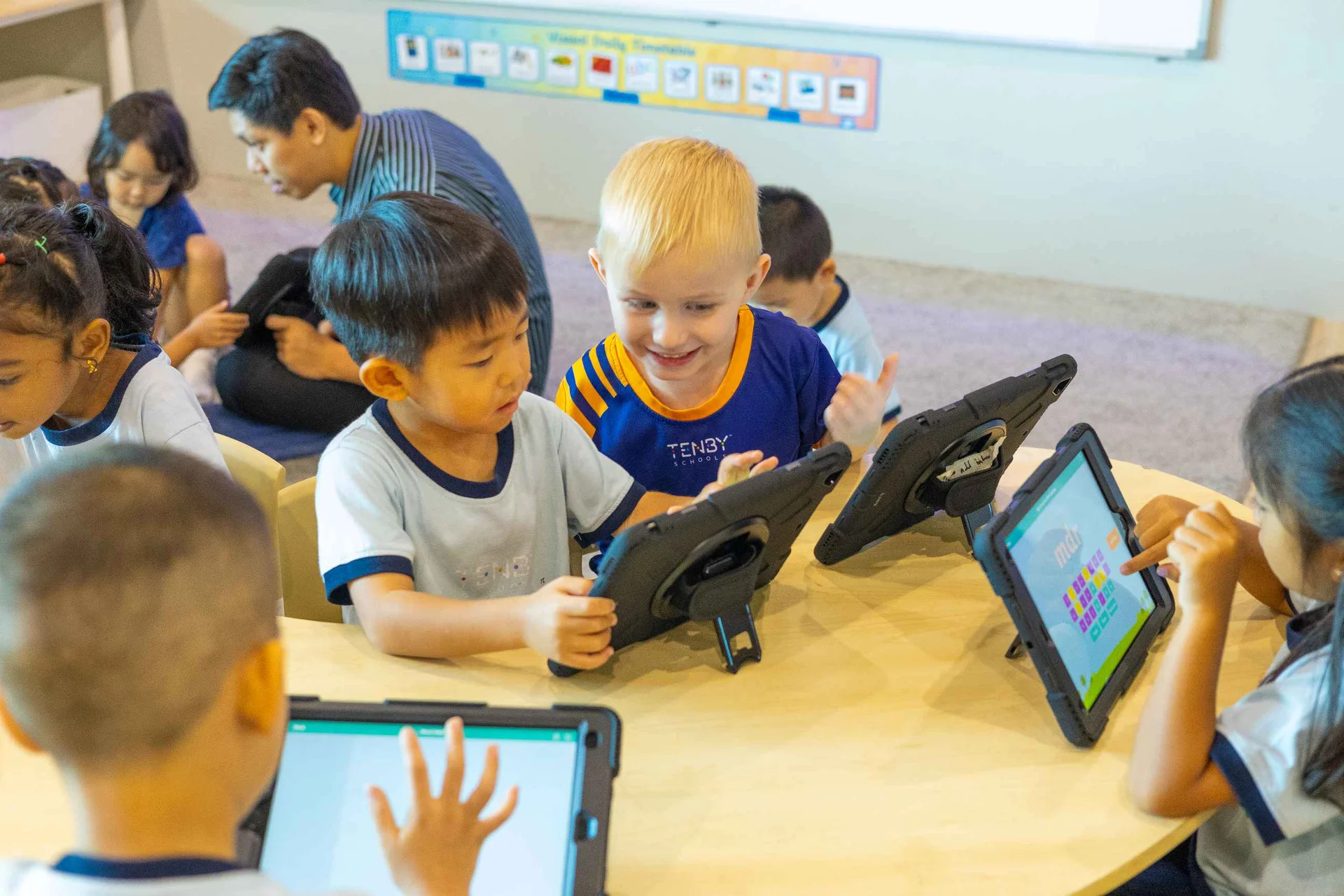 Kindergarten students playing with a tablet