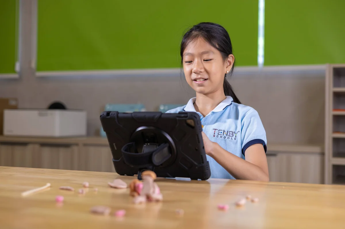 Tenby Schools student smiling while using a tablet
