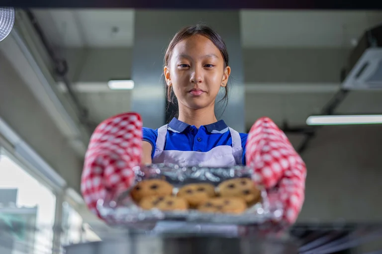 Girl taking cookies out of the oven
