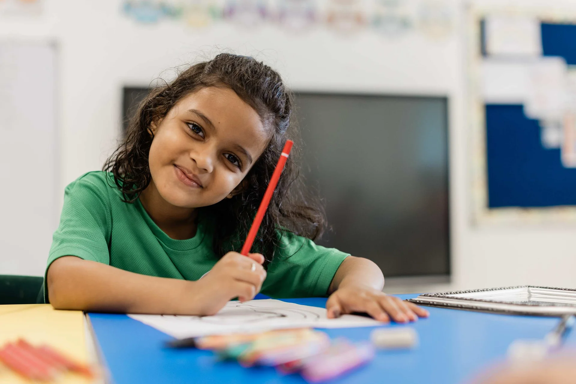 Girl looking at the camera and smiling while drawing