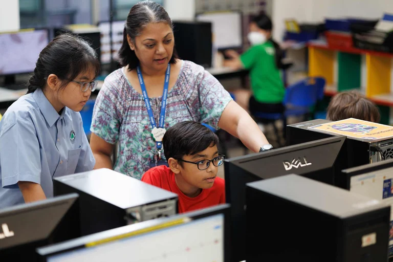 Students looking at a computer screen with their teacher